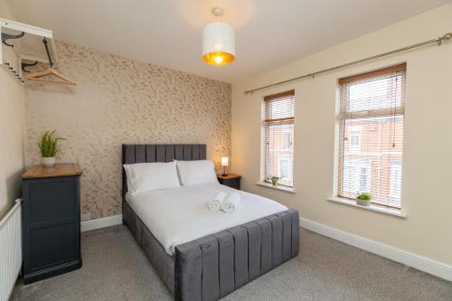 1 dormitorio con 1 cama con sábanas blancas y ventanas en Three Bedroom Apartment - Contractors & Groups welcome in Northampton by Centro Stays - Free WiFi & Parking en Northampton