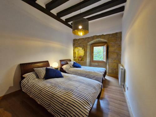 um quarto com 2 camas e uma parede de pedra em Casa de la tía Irene em Briñas