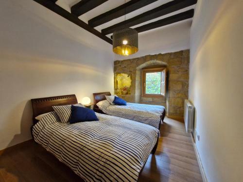 a bedroom with two beds and a stone wall at Casa de la tía Irene in Briñas