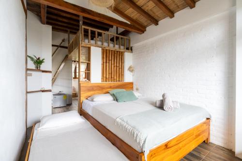 a bedroom with a bed with white walls and wooden floors at Ganso & Búho in Ayampe