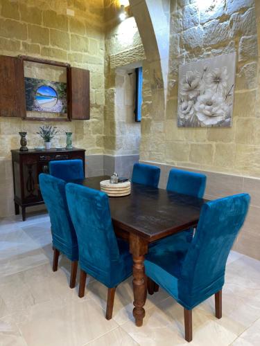 a dining room with a wooden table and blue chairs at Daner Ta’ Pantu House in Kerċem