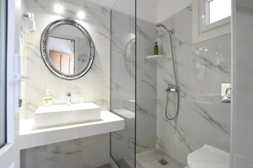 La salle de bains blanche est pourvue d'un lavabo et d'une douche. dans l'établissement Asteri Hotel, à Ornos