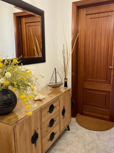 a wooden dresser with a mirror and flowers on it at El paraíso in Raxo