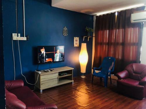 a living room with a tv and a blue wall at NR Guest House in Kangar