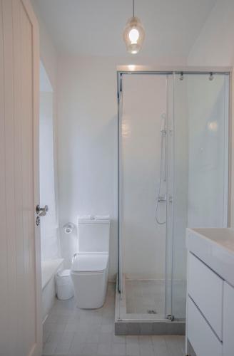 a white bathroom with a shower and a toilet at Militiko in Himare