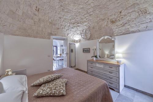 ein Schlafzimmer mit einem Bett und eine Kommode mit einem Spiegel in der Unterkunft Trulli Elios in Cisternino