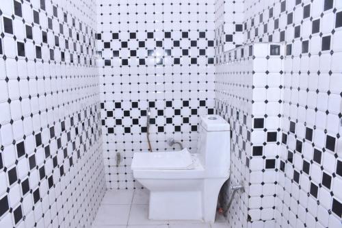 y baño con aseo y azulejos blancos y negros. en Hotel Adarsh Residency Mangalam Group, en Haridwar