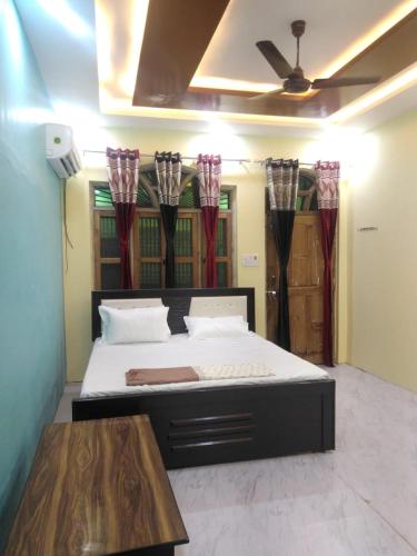 a bedroom with a bed and a table and curtains at Shyama Sadan in Ayodhya