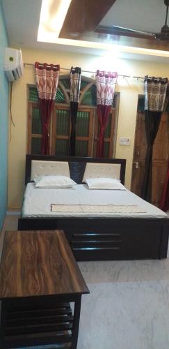 a bedroom with a bed and a wooden table at Shyama Sadan in Ayodhya