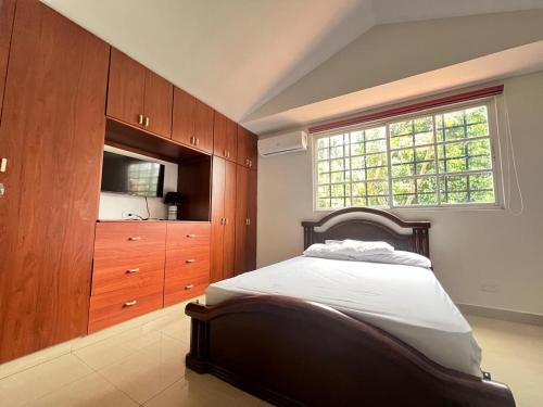 a bedroom with a bed and a dresser and a window at Habitación privada in Panama City