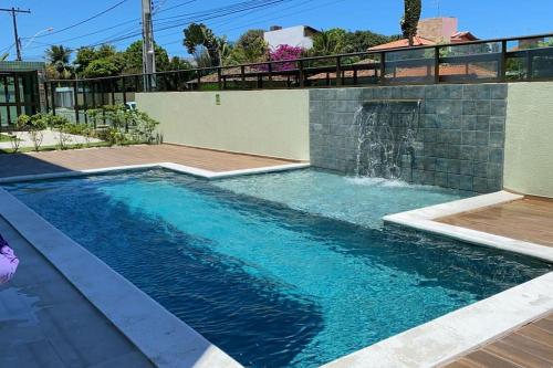 einen Pool mit Wasserfall in einem Haus in der Unterkunft Apartamento Praia do Francês in Marechal Deodoro