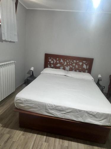 1 dormitorio con 1 cama grande con sábanas blancas en PM 1 Via Valle Canestra Guest House, en Colonna