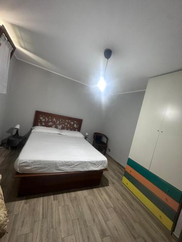 1 dormitorio con cama y pared blanca en PM 1 Via Valle Canestra Guest House, en Colonna