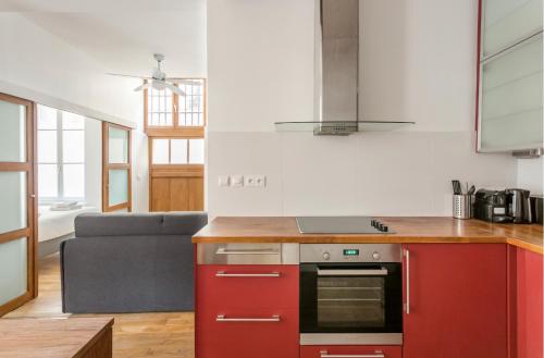 Il comprend une cuisine équipée d'une cuisinière rouge. - un four à côté d'un canapé dans l'établissement Suite Du Lion/AC Historic Flat, Marais, 4-5 Guests, à Paris