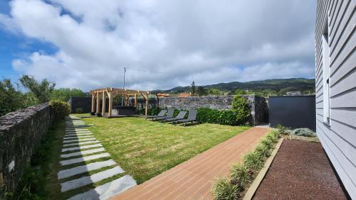 um jardim com cadeiras e uma parede de pedra em Casas de Campo Lomba D' Água - Turismo Rural em Candelária