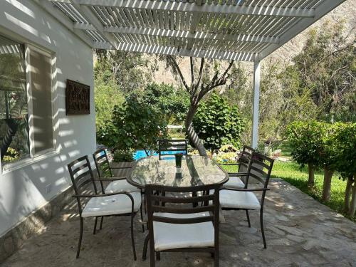 a patio with a table and chairs under a pergola at Hotel Los Palomos in Lunahuaná