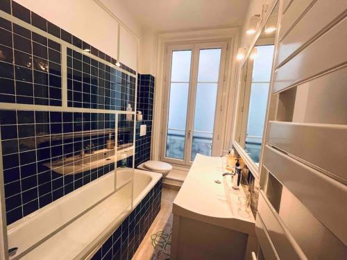 une salle de bain avec une baignoire, un lavabo et des toilettes dans l'établissement Appart d'exception Quai de seine, à Paris