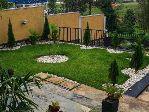 un jardin avec de la pelouse, des arbres et une clôture dans l'établissement Furnished House at Kibagabaga, à Kigali