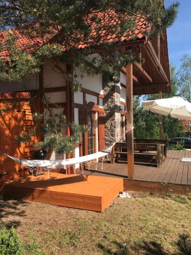 a house with a porch and an umbrella at Kaszuby domek Czerwona Koza in Barkocin