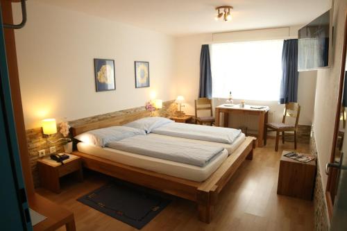 a bedroom with a bed and a table and a window at Hotel Paradis-Leukerbad-Therme in Leukerbad