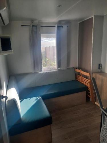 Cette petite chambre dispose d'un banc bleu et d'une fenêtre. dans l'établissement Charmant mobil home premium L048, à Narbonne