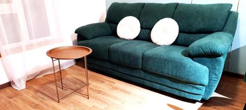 ein grünes Sofa mit zwei weißen Kissen und einem Tisch in der Unterkunft Mogosoaia High Living Mansion in Chitila