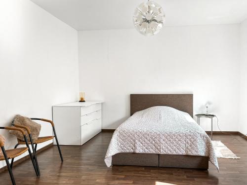 a white bedroom with a bed and a chair at Im Herzen von Wermelskirchen II in Wermelskirchen