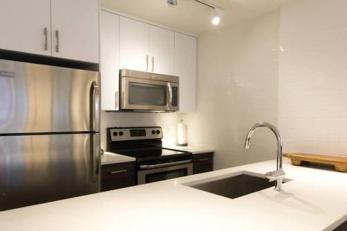 a kitchen with a sink and a stainless steel refrigerator at Bear Lodge, Whistler Village - Spectacular Location on Village Stroll, Designer Remodel in Whistler