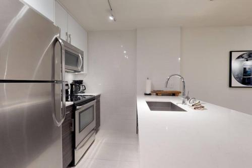 a white kitchen with a refrigerator and a sink at Bear Lodge, Whistler Village - Spectacular Location on Village Stroll, Designer Remodel in Whistler