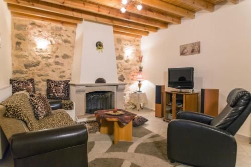 a living room with leather furniture and a fireplace at Cosy stone-built home “Hellen” in Krousón