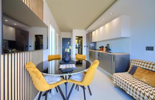 a kitchen and living room with a glass table and yellow chairs at Apartments Sinisa - Krk Town in Krk