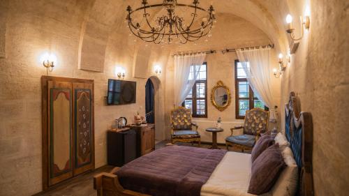 a bedroom with a large bed and a chandelier at Yeşil Konak Cave Hotel in Ürgüp