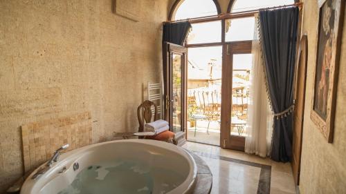 a bathroom with a tub and a large window at Yeşil Konak Cave Hotel in Ürgüp