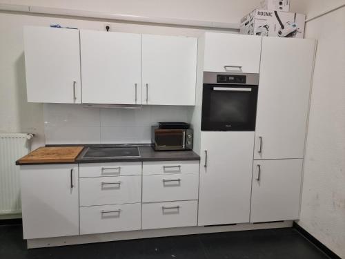 een keuken met witte kasten en een zwart apparaat bij غرفة مميزة في موقع مميز in Bonn
