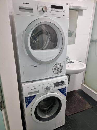 een wasmachine en droger in een badkamer met een wastafel bij غرفة مميزة في موقع مميز in Bonn
