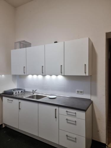 a white kitchen with a sink and white cabinets at غرفة مميزة في موقع مميز in Bonn