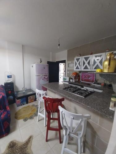 a kitchen with a counter and some chairs in a room at Tavira شاليه in Ras Sedr
