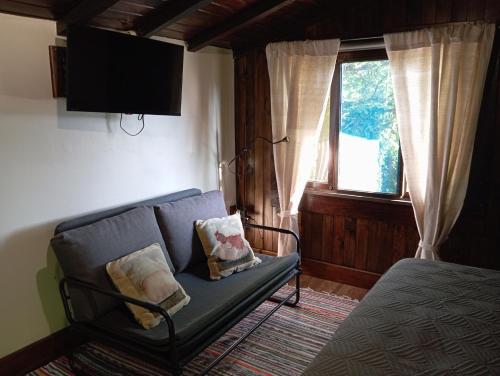 sala de estar con sofá y ventana en O Cantinho de Coura - a cabana, en Paredes de Coura