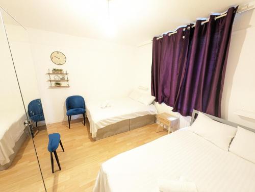 a bedroom with two beds and a window with purple curtains at Tobacco Docks & St Katherine's Rooms in London