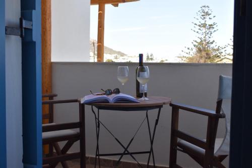 a table with two wine glasses and a book at Asterias Studios in Agia Anna Naxos