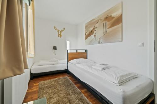 twee bedden in een kamer met witte muren en een tapijt bij Residence Alpin Kaprun - Top 6 by Four Seasons Apartments in Kaprun