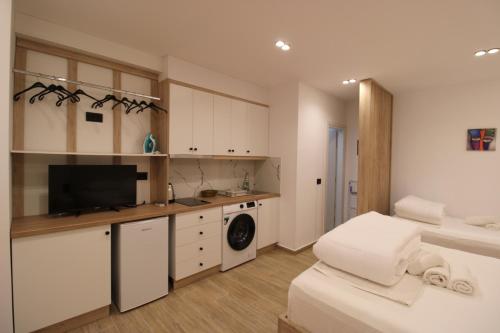 a kitchen with white cabinets and a washer and dryer at Reni Risi Deluxe Studio in Sarandë