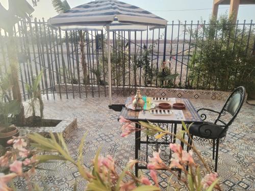uma mesa e cadeira com um guarda-sol num jardim em DAR SARSAR airport em Marraquexe