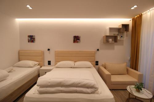 a bedroom with two beds and a chair at Reni Risi Deluxe Studio in Sarandë