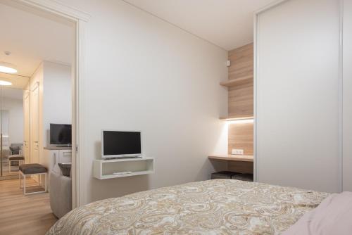 a bedroom with a bed and a tv on a wall at Cathedral apartment, perfect for couples in Vilnius