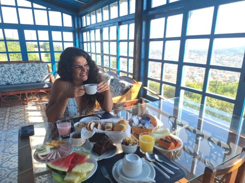 una donna seduta a un tavolo con un piatto di cibo di Pousada Tanto Mar ad Arraial do Cabo