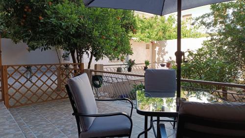 um pátio com uma mesa, cadeiras e um guarda-sol em Katerina Holiday House em Anavissos