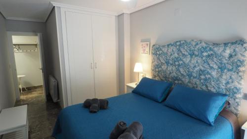 Un dormitorio con una cama azul con un osito de peluche. en Bonito apartamento en centro ciudad con garaje, en Albacete