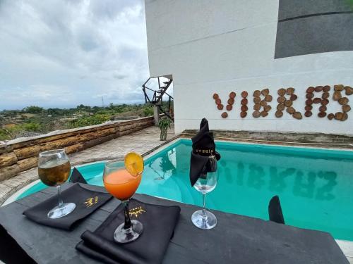 Vibras Eco Hotel في بوبايان: طاولة مع كأسين من النبيذ بجوار حمام سباحة