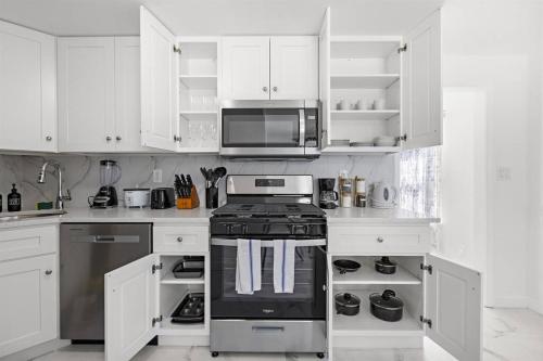 a white kitchen with a stove and a microwave at Comfy Cozy retreat - NYC & NWK w free parking in Bayonne